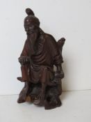 A carved Oriental wooden figurine of a man.