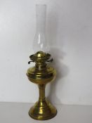 A brass oil lamp with glass chimney.