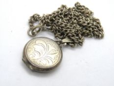 A round silver locket having floral engraving on silver chain.