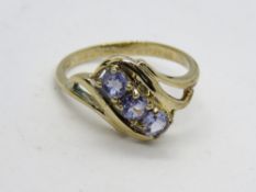 A 9ct gold three stone iolite ring, each stone being a pale lilac round cut in claw setting,