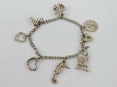 An HM silver charm bracelet having part padlock clasp and seven charms upon,