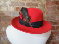 A 100% wool hat in red with feathers upon.