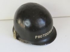 A US M1 helmet with WWII liner, has photographer on both the helmet and liner.