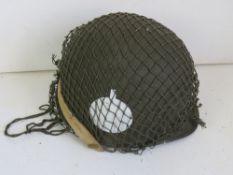 A Vietnam US M1 helmet with netting and chin strap.