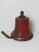 A red painted cast iron bell with clange