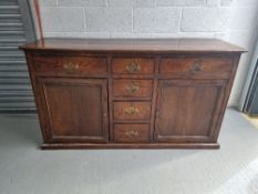 An oak dresser base having four central drawers with drawer and door flanking,