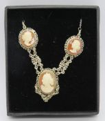 A delightful cameo necklace featuring three carved shell portraits in white metal filigree mounts.