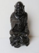 A carved Oriental wooden figurine of a deity.