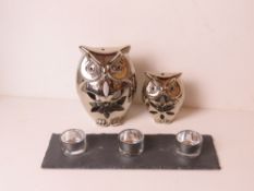 A pair of graduated silver painted owl tealight holders together with a trio of glass tealights on