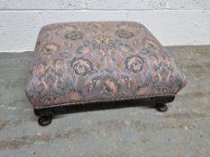 A low footstool upholstered in blue and purple fabric in the Liberty style.