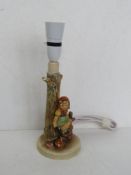 A Goebel late 20thC lamp base having little girl with basket sat on a fence,
