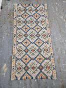 A hand woven rug in yellows, blues and greens measuring approx. 142 x 70cm.