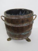 A coopered and copper banded bucket having brass lion paw feet and twin side handles,