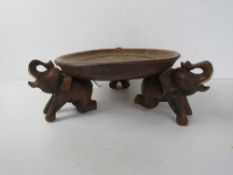 A hand carved centrepiece dish raised over 3 elephant shaped supports approx. 36cm wide .