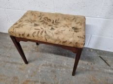 A piano stool with floral fabric seat.