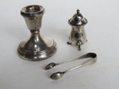 A hallmarked silver short candlestick together with HM silver pepperette, and HM silver sugar tongs.