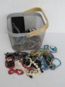 A quantity of assorted costume jewellery inc bangles, beaded necklaces, etc. All within wire basket.