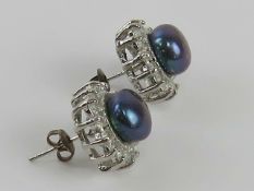 A pair of black coloured pearl stud earrings with CZ stones surrounding each pearl,