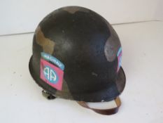 A US M1 helmet with Airborne decals either side, and a line dated 1955.