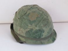 A US Vietnam M1 Para helmet with a Mitchell camo cover and foliage band.