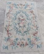 A vintage woollen rug in floral pattern on cream ground, for cleaning. Measuring approx 153 x 93cm.
