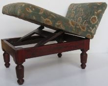 An antique gout stool having green floral velvet upholstery.