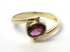 A 9ct gold garnet ring, the rubover set oval cut garnet approx 7 x 5mm in wrap style setting,