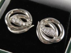 A pair of silver earrings, each in the form of a coiled snake, with white stone heads,