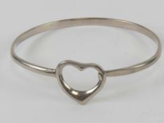A hallmarked silver bangle having heart design clasp, HM for London, 5.6 x 5.2cm internal dia, 12.