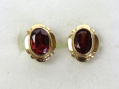 A pair of garnet stud earrings, oval cut stones in rubover settings, no apparent hallmark,