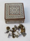 An inlaid jewellery box opening to reveal a quantity of assorted cufflinks within.