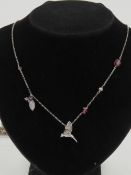 A silver necklace having hummingbird pendant, pearl, crystal and floral decoration upon,