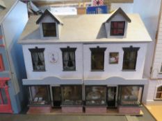 A delightful decorated and furnished dolls house in the form of two shops with homes over,