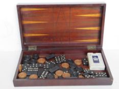 An inlaid wooden chess / draughts / backgammon board opening to reveal various pieces within.