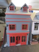 A dolls house furnished as a public house with home over, outside sign and lamp, barrel cart,