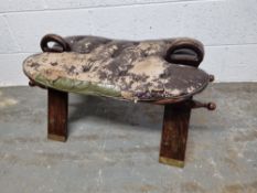 A camel stool in need of re-upholstering having brass inlay throughout.
