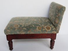 An antique gout stool having green floral velvet upholstery.