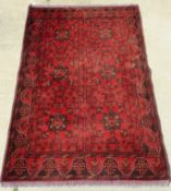 A red ground woollen rug in floral geometric pattern measuring approx 200 x 132cm.
