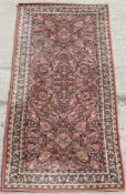 A 100% pure virgin wool rug bearing label to back in terracotta ground with floral pattern upon and