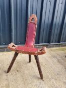 A carved wooden three legged high backed stool having leatherette seat.