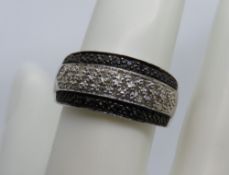 A 9ct white gold ring encrusted with black and white stones, size R, hallmarked 375, 3.1g.