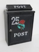 A black metal letter box with rose design to front with key.
