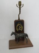 A vintage table lamp having cast metal horse and horse brass over wooden base, for rewiring,