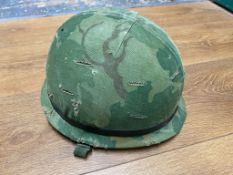 A US Vietnam era M1 helmet with liner and twill cover, chin strap marked with a P. This lot will