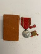 A WWII Japanese red cross medal and lapel badge in box.