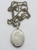 A hallmarked silver locket having part floral engraving to front, on white metal chain.