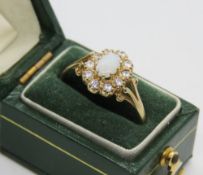 A 9ct gold opal cluster ring, the central opal cabachon surrounded by a gallery of white stones,