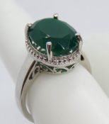 A silver and green stone solitaire cocktail ring, pierced gallery with halo design setting,