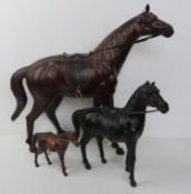 A set of three leather covered horses, each having saddle and bridle upon,