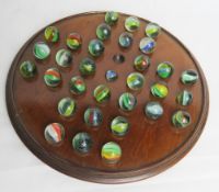 A mahogany solitaire board with hand blown glass marbles.